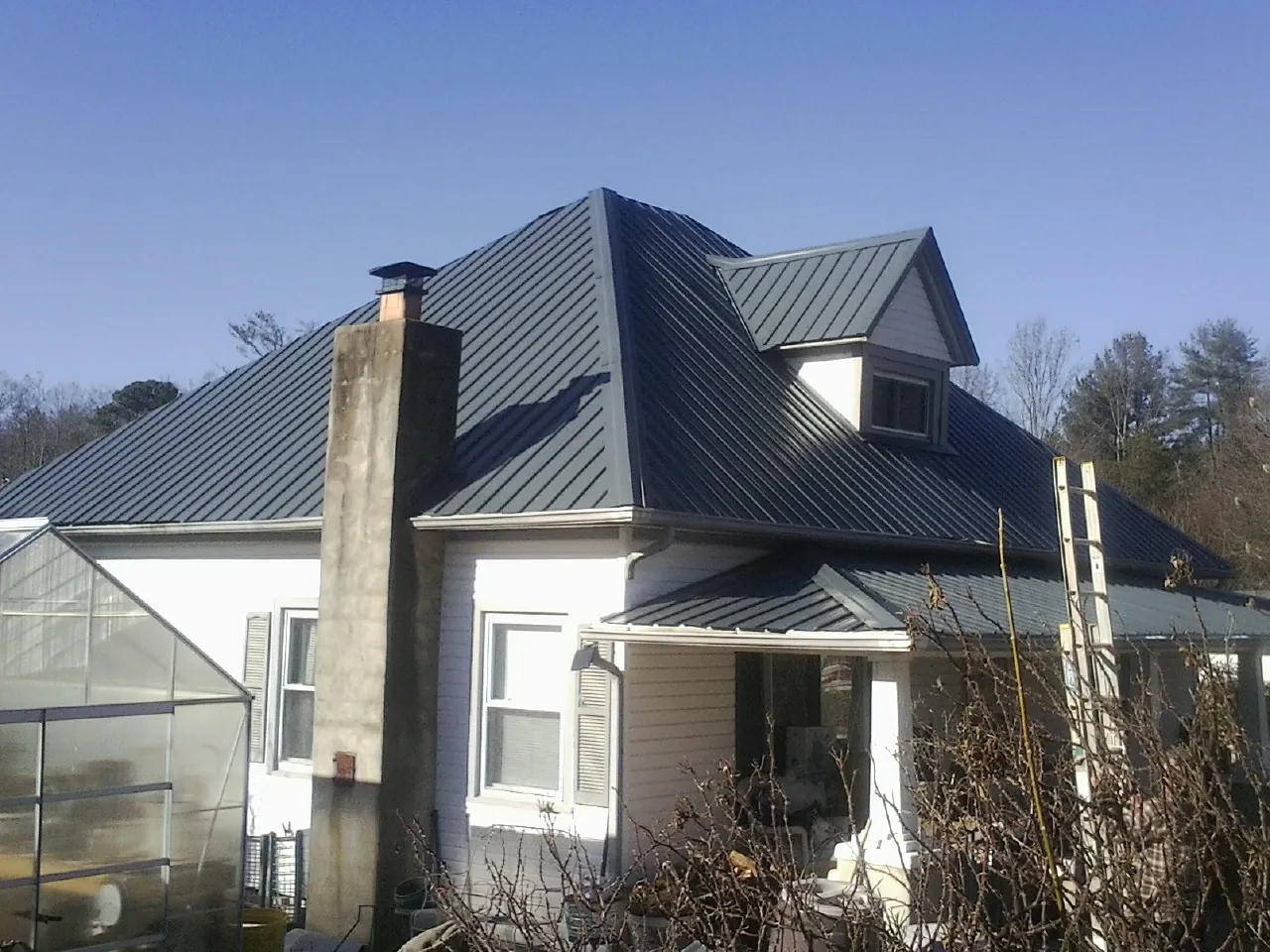 Dark blue standing seam metal roof on a white farmhouse with dormer — Slate & Tile Roof Repair by Roofing Brothers in Cobb Island