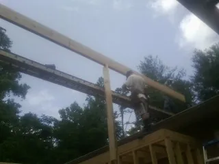Carpenter setting a ridge beam over a new addition frame — Ice Dam Removal by Roofing Brothers in Cobb Island