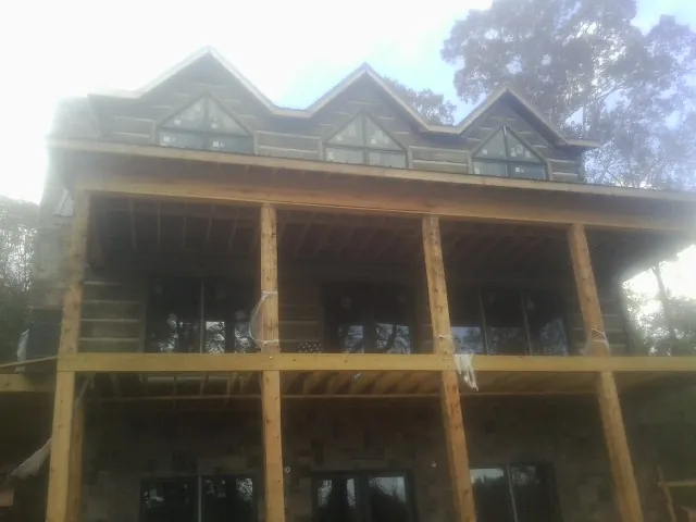 Dormers and porch framing on a large log home under construction — Roof Coating work by our crew in Cobb Island