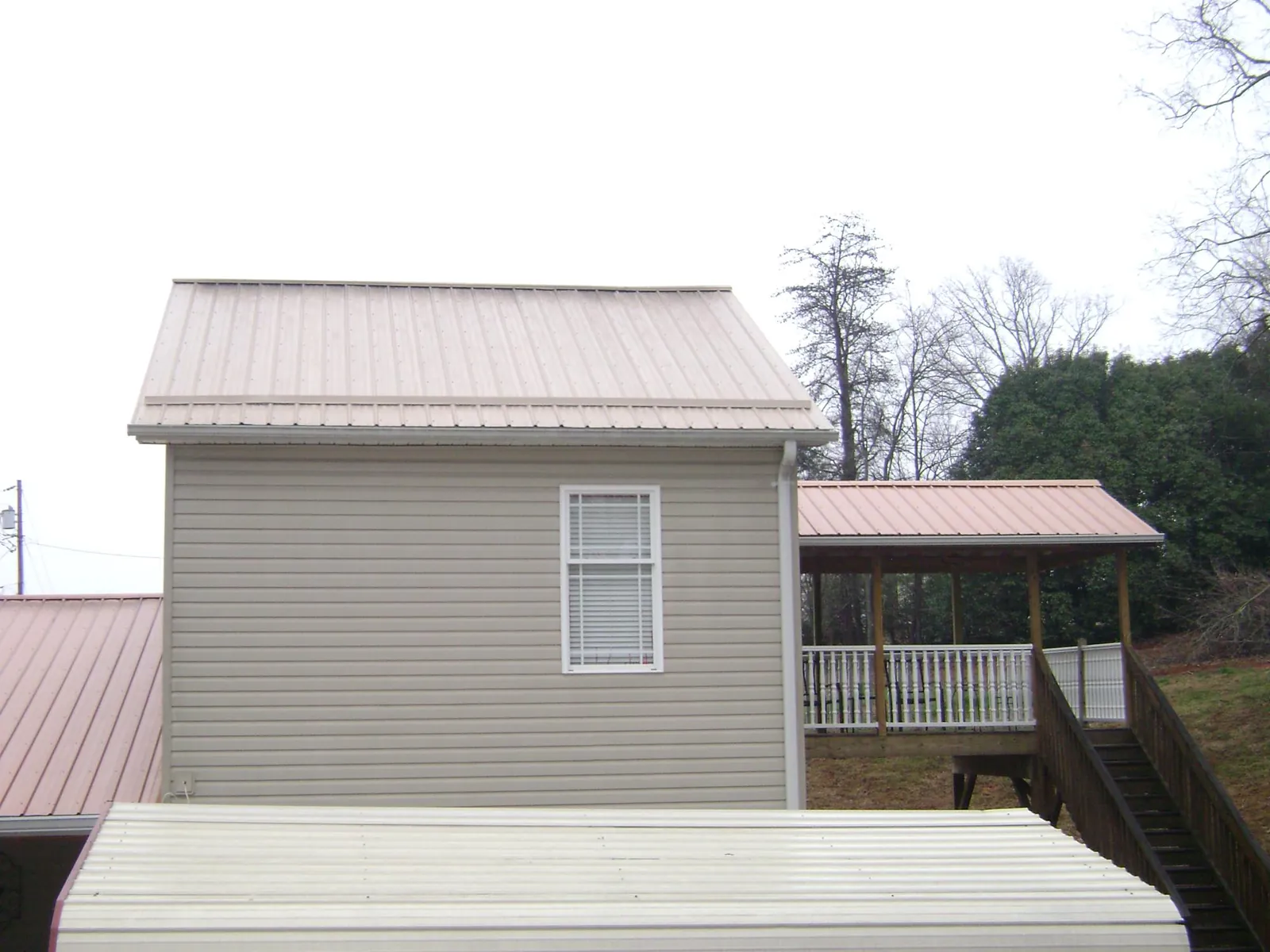 Tan metal roofs on a two story addition and attached porch, from a Roof Replacement job in Cobb Island
