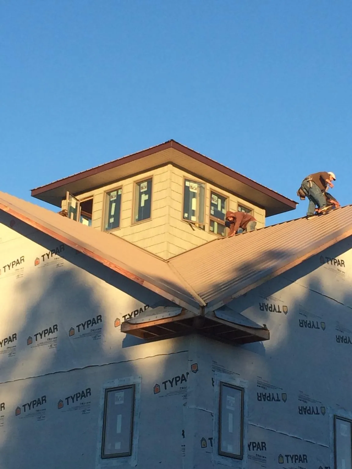 Roofers working around a rooftop cupola on a new metal roof at sunset — Roof Waterproofing in Cobb Island by Roofing Brothers